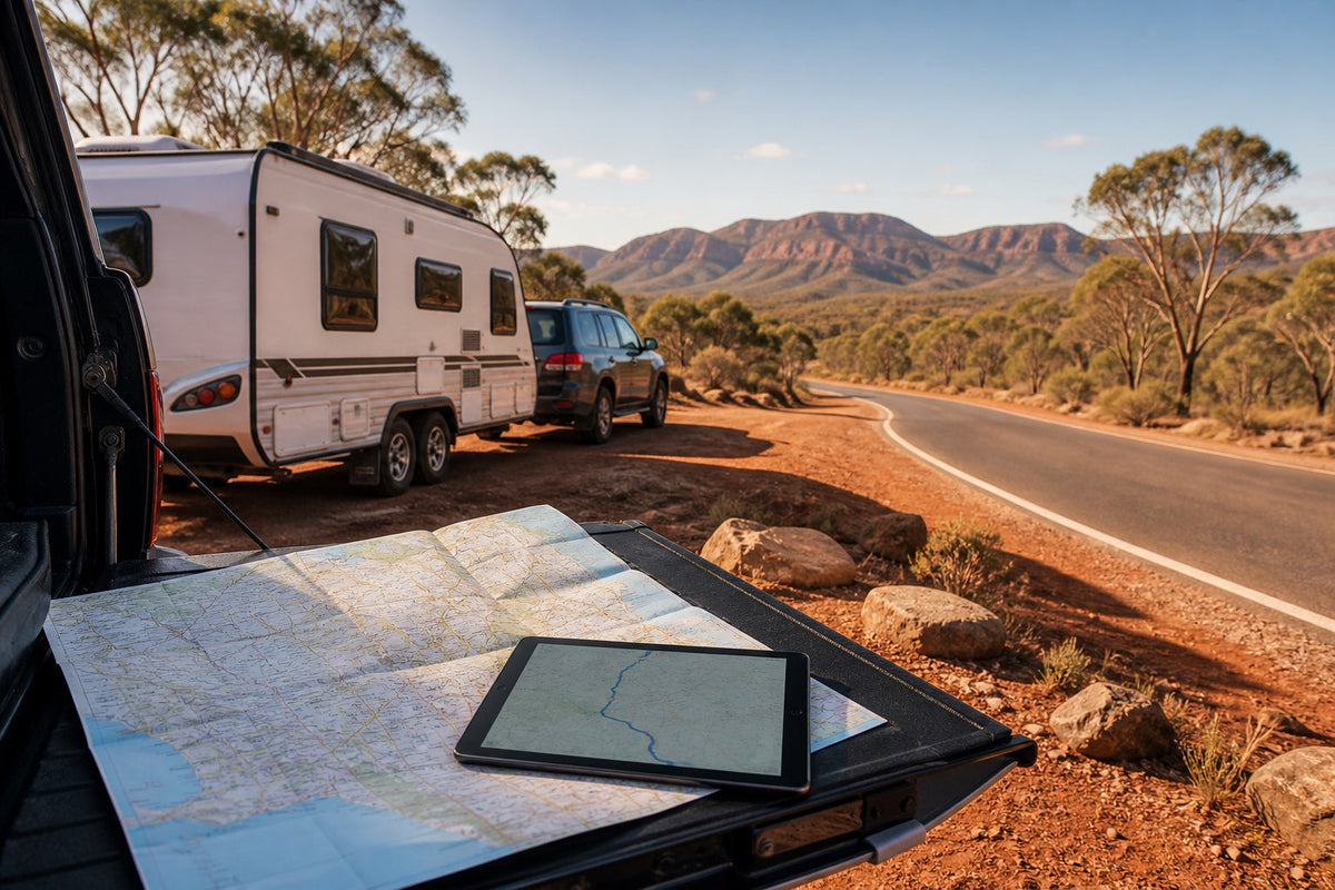 Paper map and tablet with a caravan and tow vehicle beside an Australian road