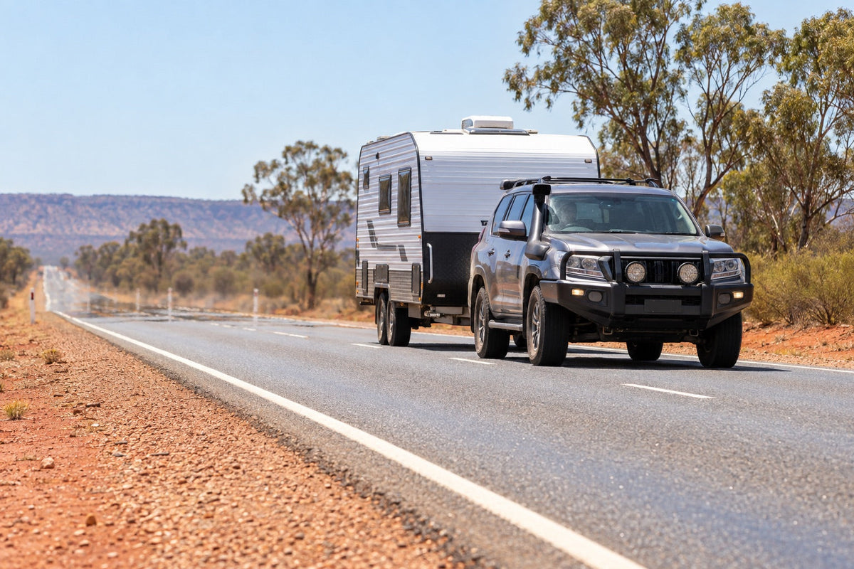 Four-wheel drive towing a caravan on a sunlit Australian inland highway