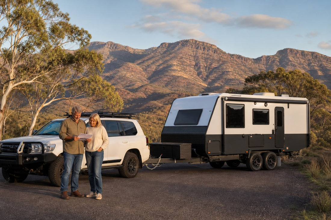 Mature couple comparing a caravan floor plan beside a white tow vehicle and caravan in the Flinders Ranges