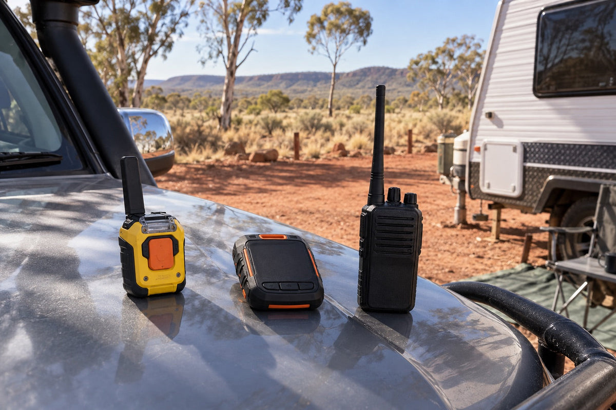 Personal locator beacon, satellite messenger and UHF radio beside a remote caravan